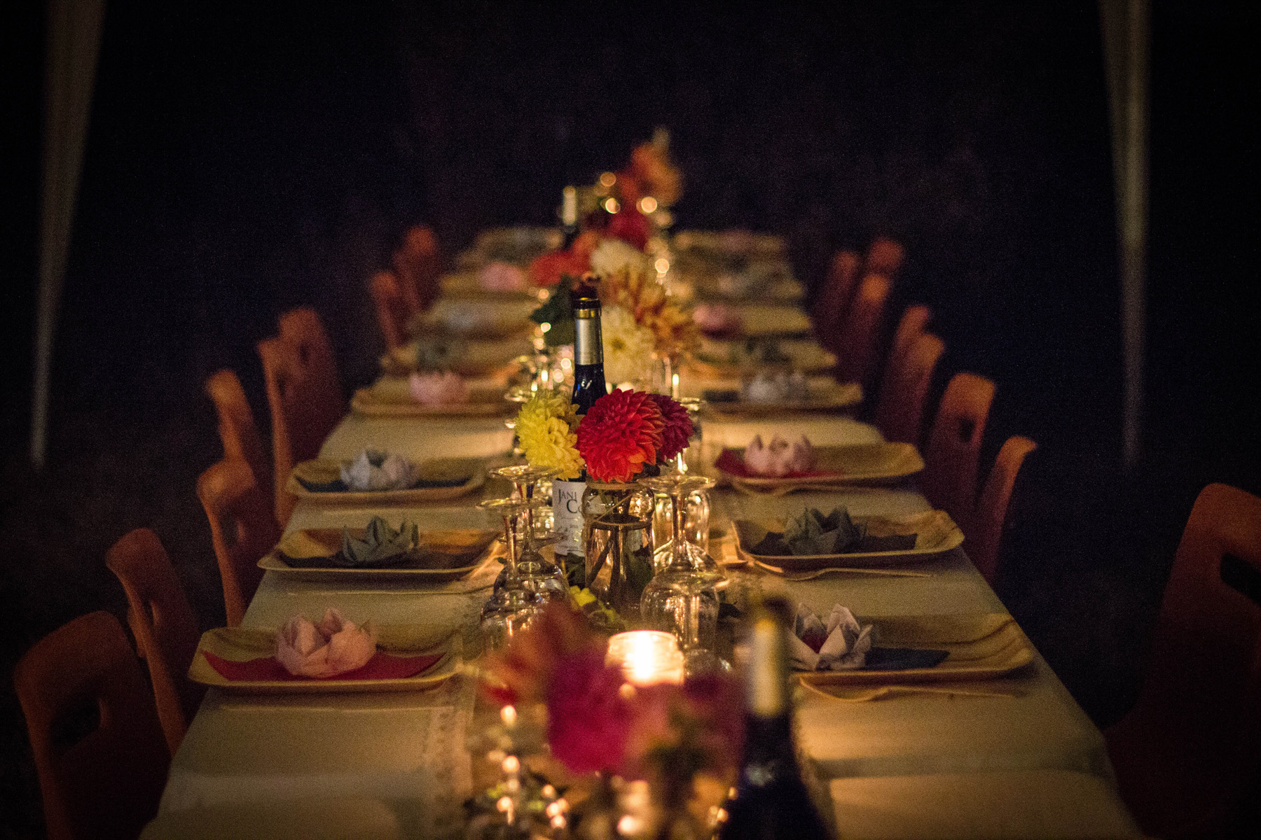 A beautifully set long wooden table with plates of food, ready for a rehearsal dinner party.