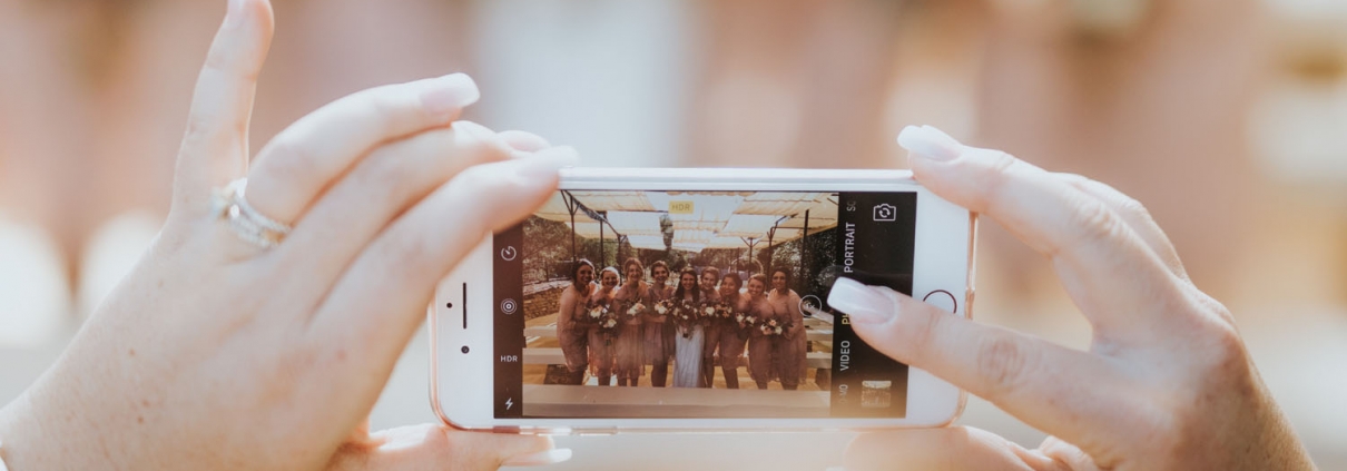 A woman's hands hold a cell phone and take a photo of a wedding